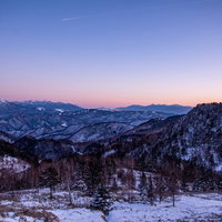 夕暮れの空と雪化粧した雪山の冬景色、山脈に映える夕焼けの写真
