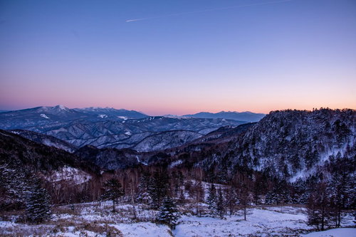夕暮れの空と雪化粧した雪山の冬景色、山脈に映える夕焼け