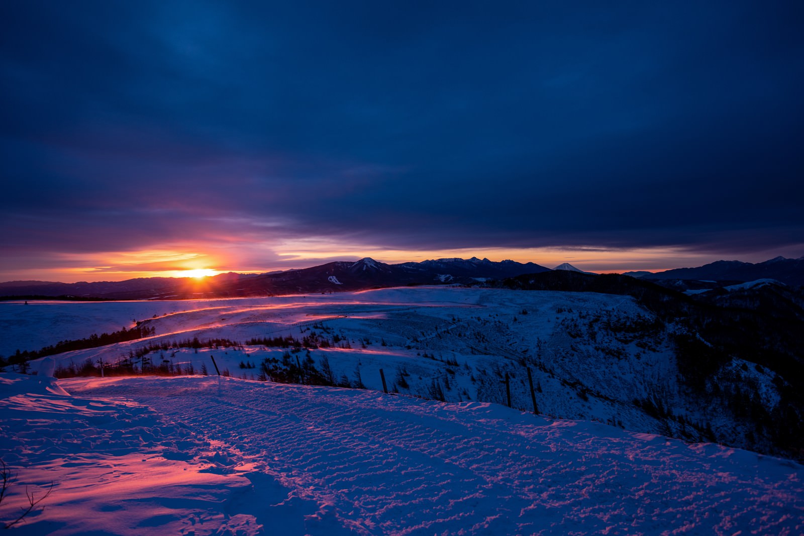 夕日に照らされて雪原が広がる冬の風景