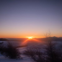 冬の美ヶ原高原に昇る夜明けの朝日と雪景色の写真