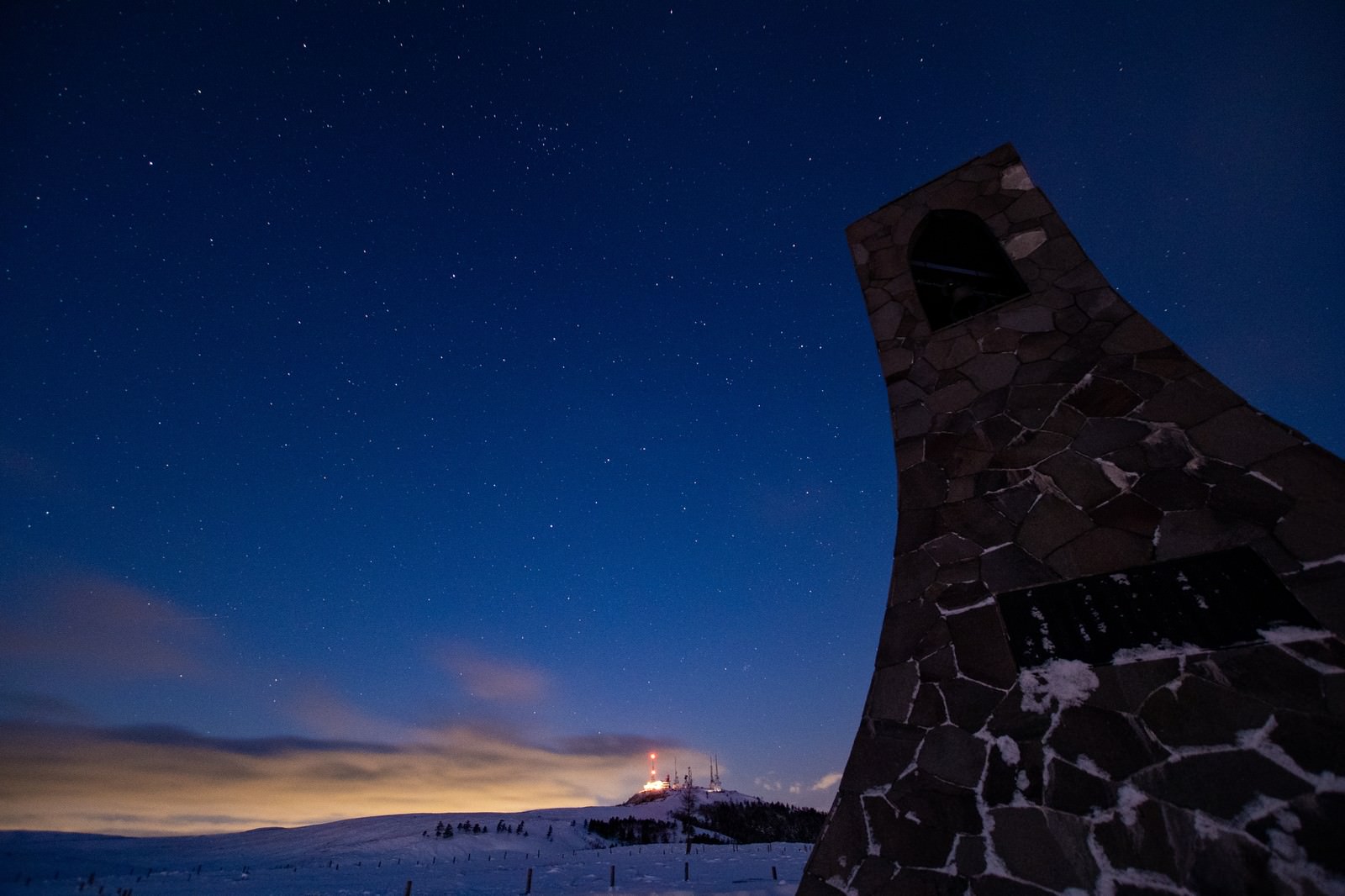 美ヶ原高原の雪原に建つ美しの塔と星空が広がる夜明け前の風景