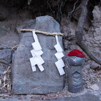 鳥屋の双体道祖神と赤い帽子の地蔵、注連縄と紙垂が飾られた洞窟内の石仏の写真