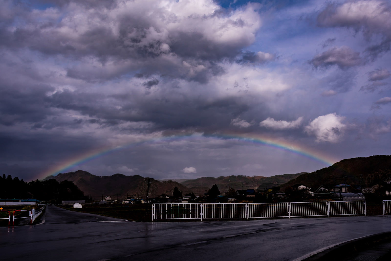 雨上がりの曇り空に現れた美しいアーチ状の虹