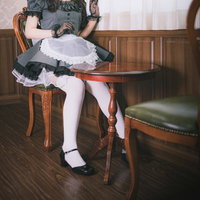 レトロな木製椅子に座る黒いメイド服の女性コスプレの写真