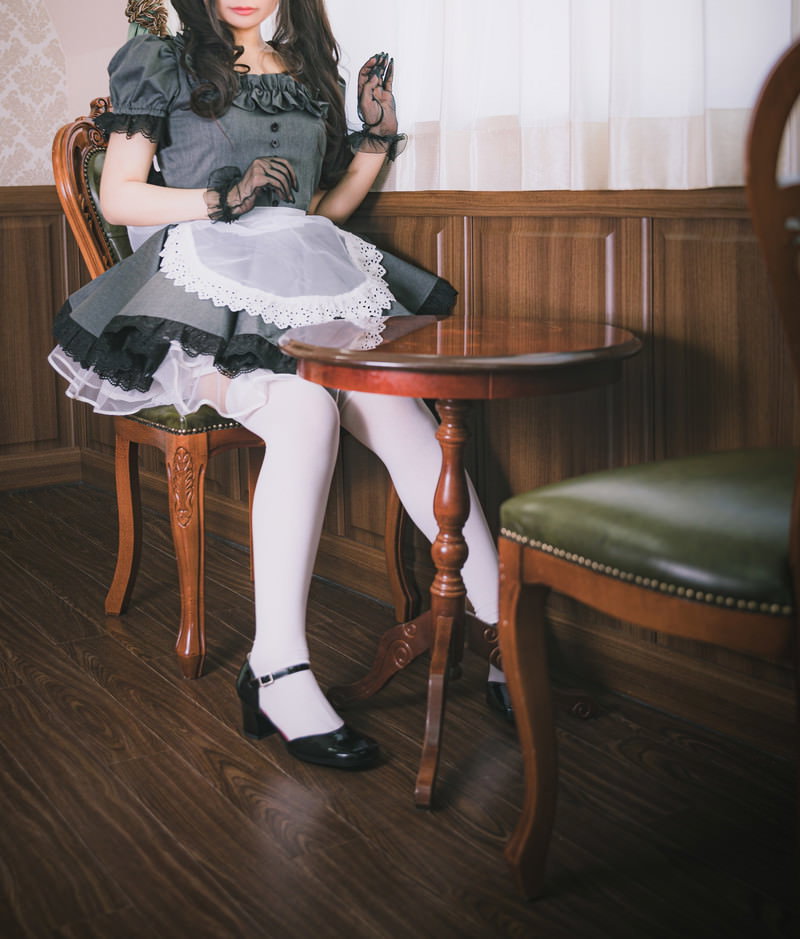 レトロな木製椅子に座る黒いメイド服を着た女性［モデル：石投げて美奈代］