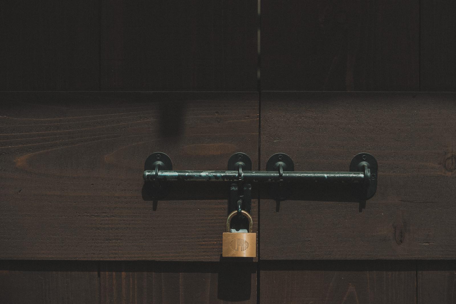 木製の扉に取り付けられた閂と南京錠