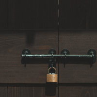 木製の扉に取り付けられた閂と南京錠の写真