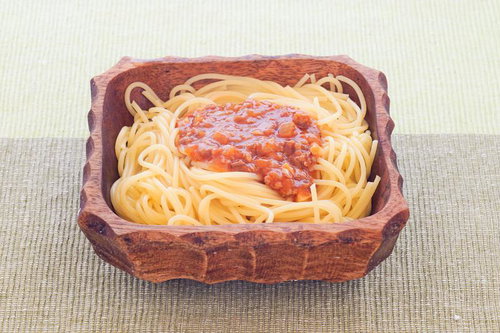 木製の器に盛りつけられたスパゲッティミートソース