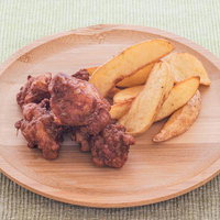 木製の丸皿に盛られた唐揚げとポテトフライの写真
