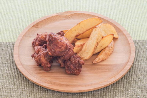 木製の丸皿に盛られた唐揚げとポテトフライ