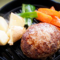 鉄板の上に置かれたハンバーグと野菜の料理の写真