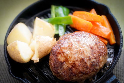 鉄板の上に置かれたハンバーグと野菜の料理