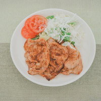 白い皿に盛られた揚げたてハムカツとキャベツの千切りの写真