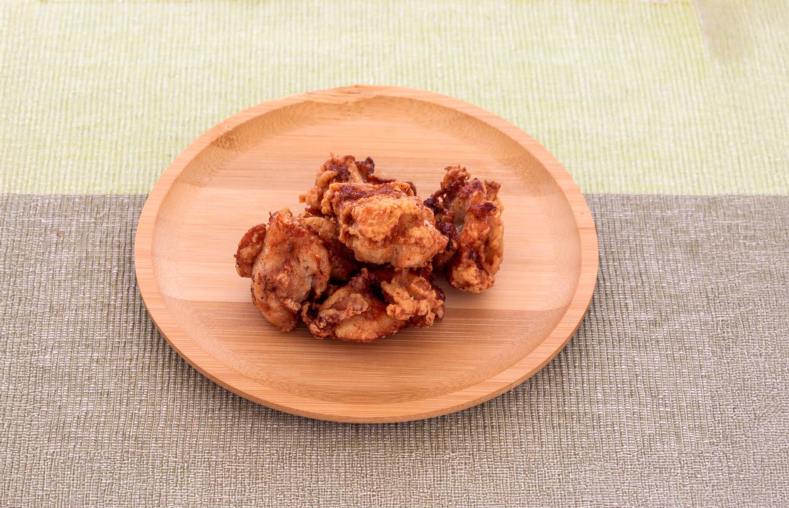 黒い陶器皿に盛られた鶏肉と大根の煮物と緑の薬味