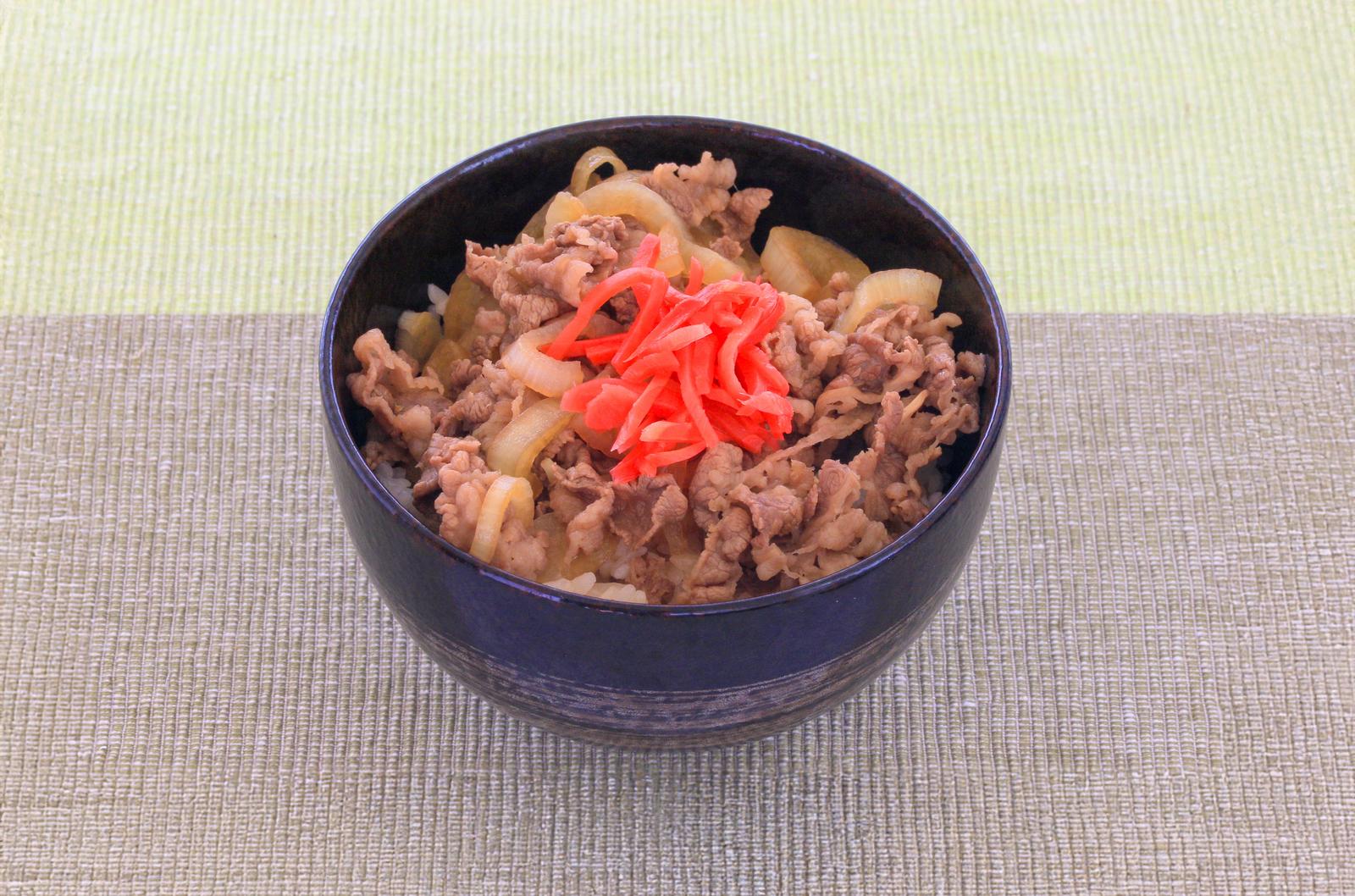 白い皿に盛られた卵入りチャーハンに紅生姜をのせた料理