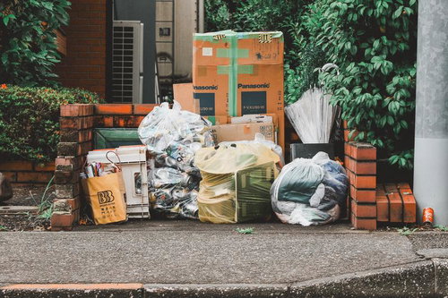 住宅街のごみ集積所に整然と並ぶ資源ごみと段ボール