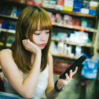 店番しながらスマホをいじる香港美女の退屈な待機時間の写真