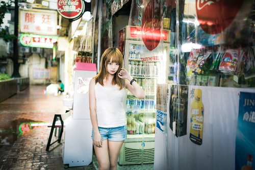 雨上がりの香港の下町にある商店で店番をするプリン髪の看板娘