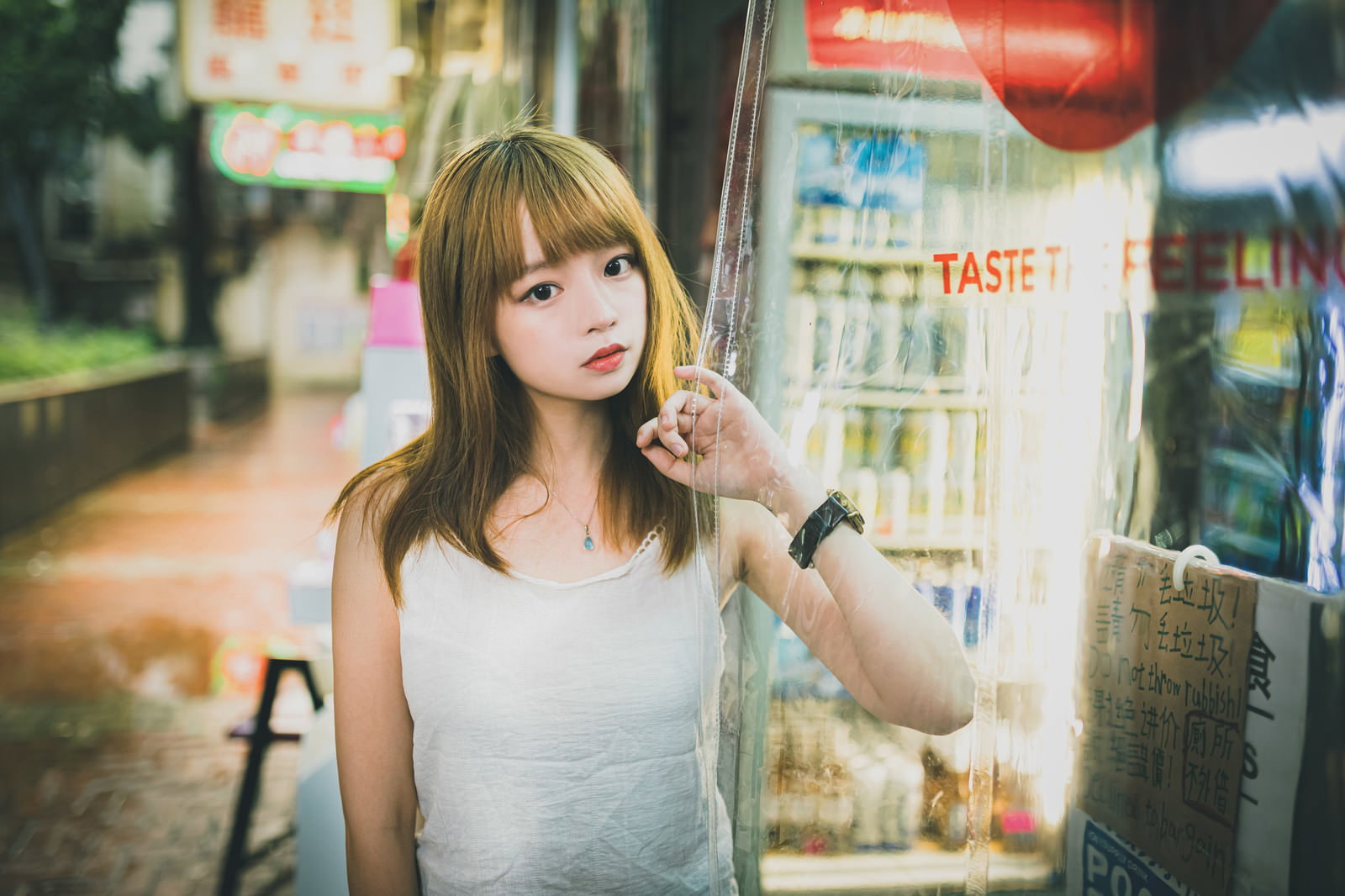 商店で外の様子を眺めるプリン髪の女性［モデル：まめち］