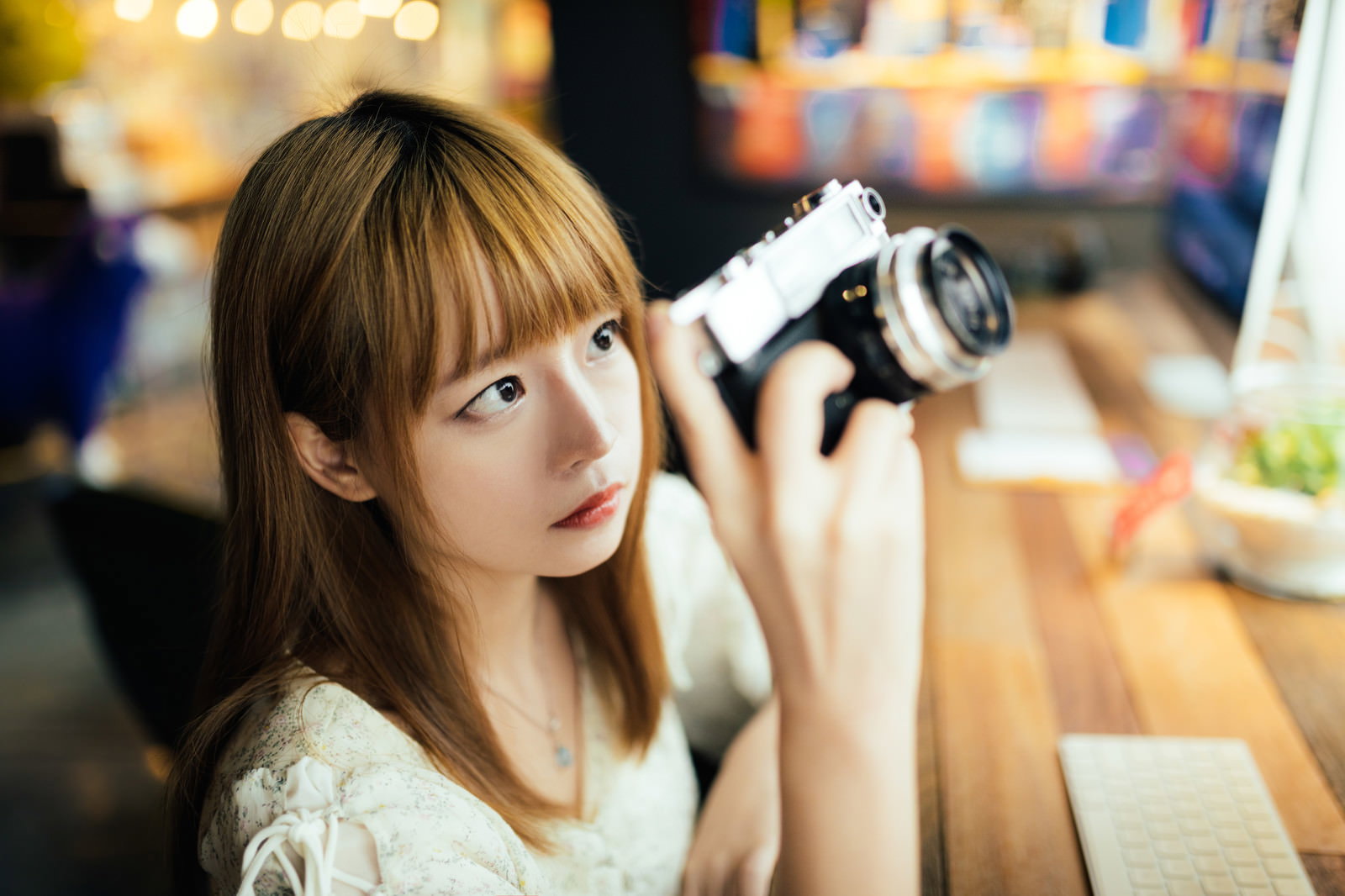 カフェでミラーレスカメラを構えて撮影ポーズを取る女性［モデル：まめち］