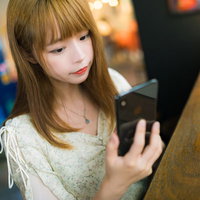 スマホのアプリ画面を確認する女性の写真