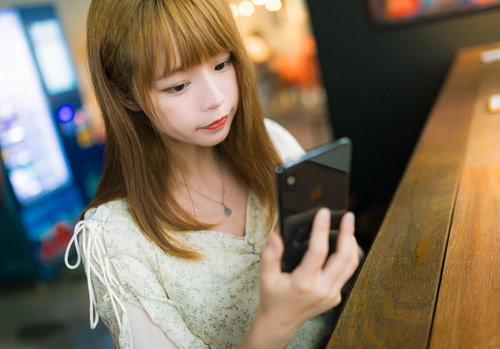スマホのアプリ画面を確認する女性