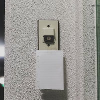 白い壁のベージュのスイッチカバーの下に貼られた白い紙のメモの写真