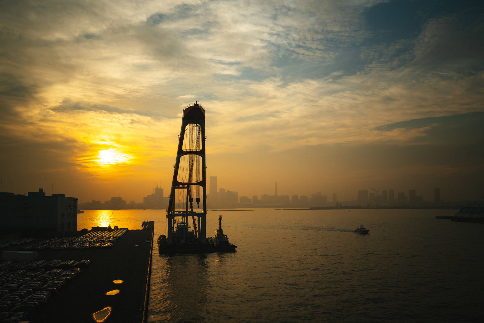 港の夕暮れ風景、水面に映る夕日と建物のシルエット