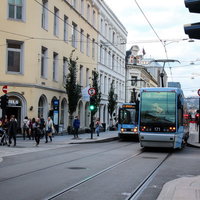 オスロの街を走る緑色の路面電車とクリーム色の建物（ノルウェー）の写真