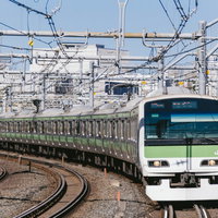 都心を走る緑の電車と複雑な架線、駅構内の線路分岐風景の写真
