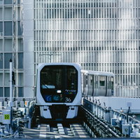 高層ビル群の中を走行するゆりかもめの車両の写真