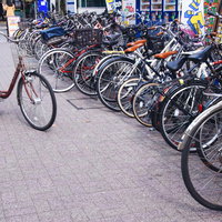 駅前の駐輪スペースに並ぶママチャリと自転車の写真