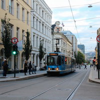 オスロの街を走る青い路面電車と歴史的建物の写真