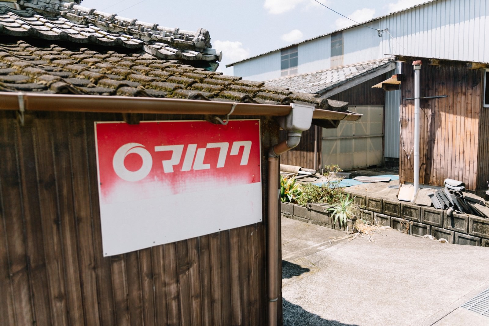古い木造民家の板壁に取り付けられた赤と白のサラ金看板