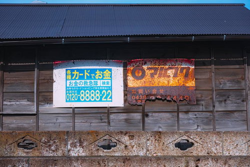 錆びて電話番号がほとんど見えなくなっている「マルフク」の看板