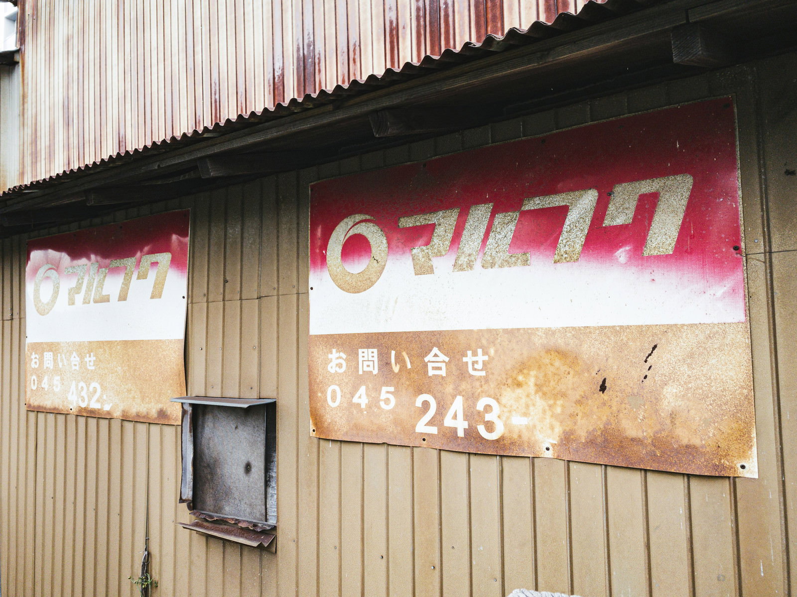 古い建物の壁に取り付けられた錆びて劣化したマルフクの看板