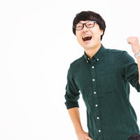 緑色のシャツでガッツポーズを決めるメガネ男子の写真