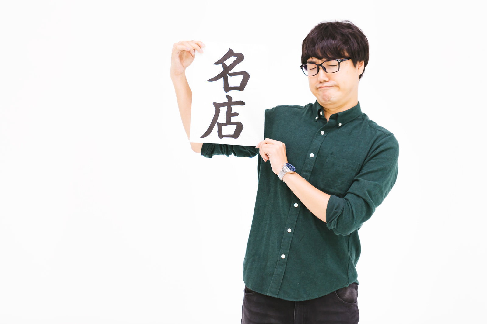 「名店」の札を掲げる緑シャツの男性が納得の表情で正面を向いている［モデル：真崎真幸］