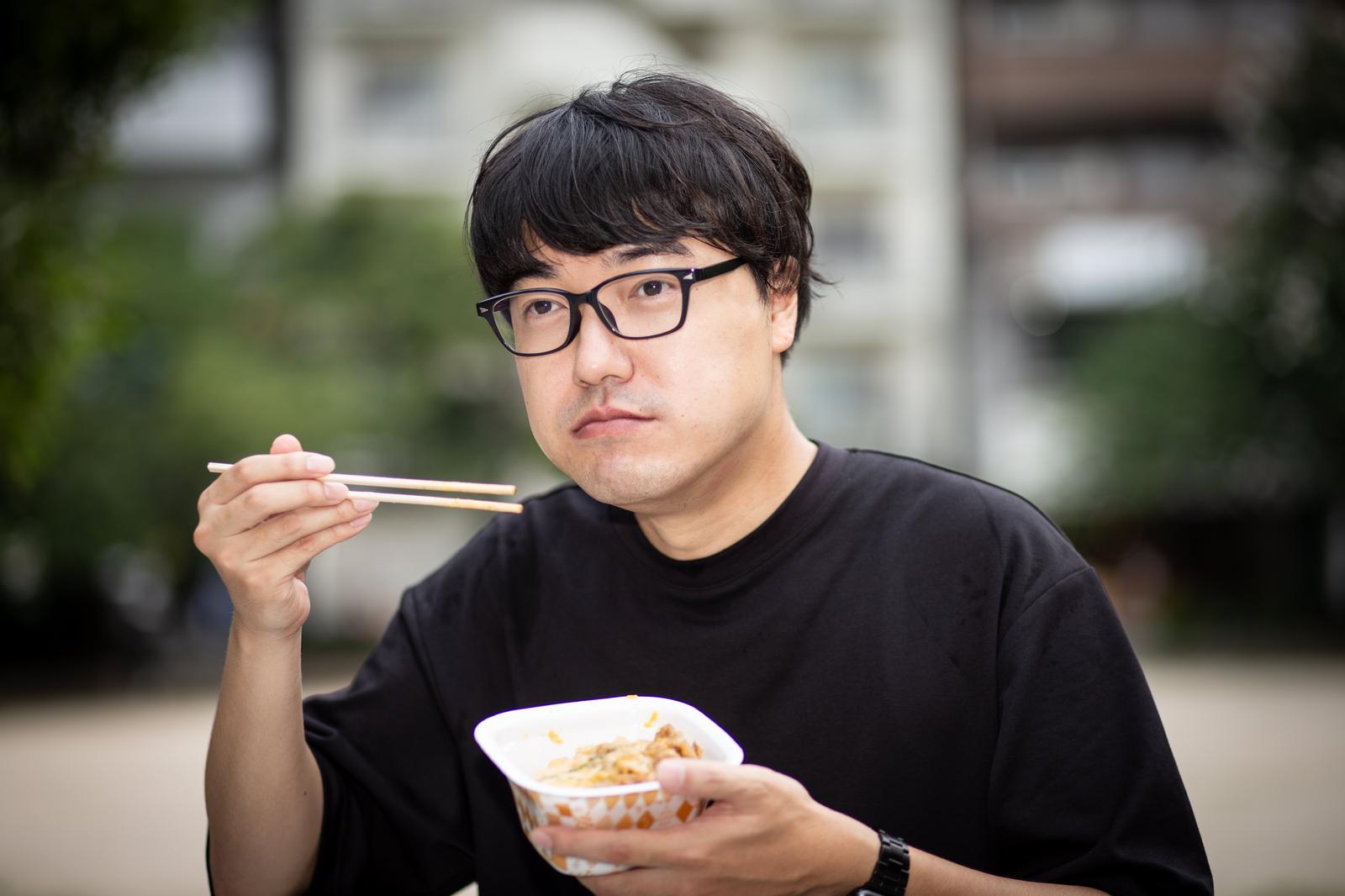 牛丼を食べる眼鏡をかけた男性スタッフ［モデル：真崎真幸］