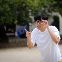 屋外で視力検査をする眼鏡をかけた男性が指差し確認の写真