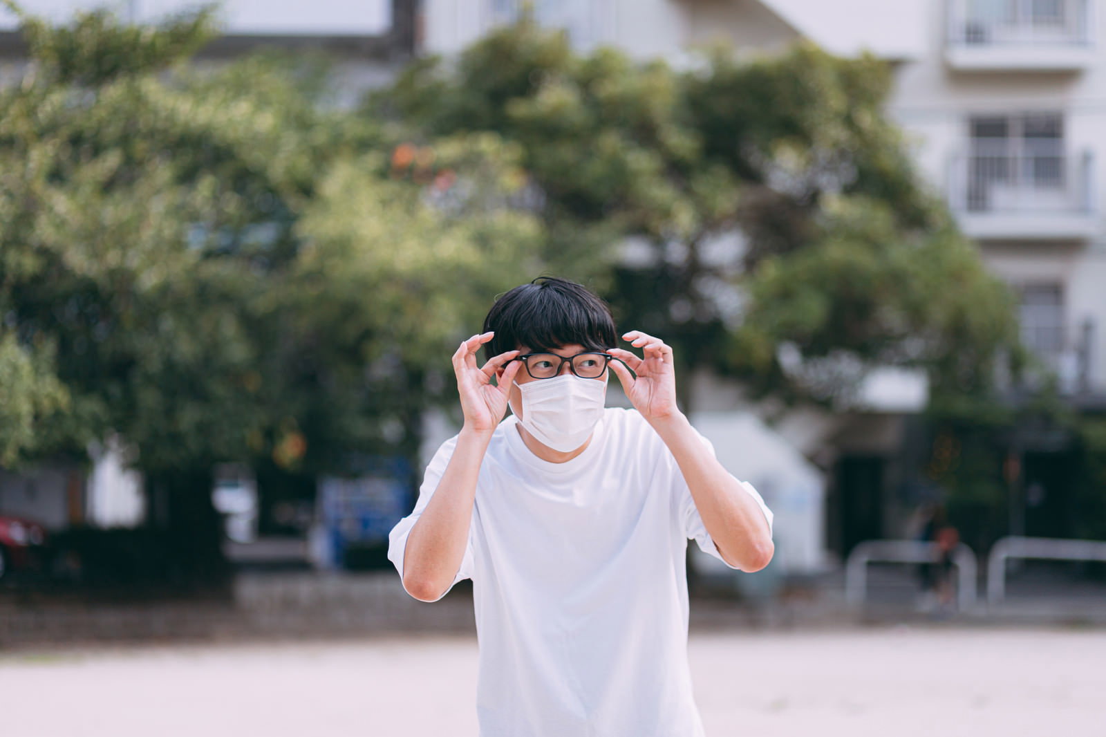 白いTシャツを着た男性が双眼鏡を使って何かを観察している［モデル：真崎真幸］