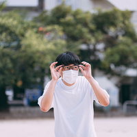 花粉を目視するマスク着用の眼鏡をかけた男性の写真
