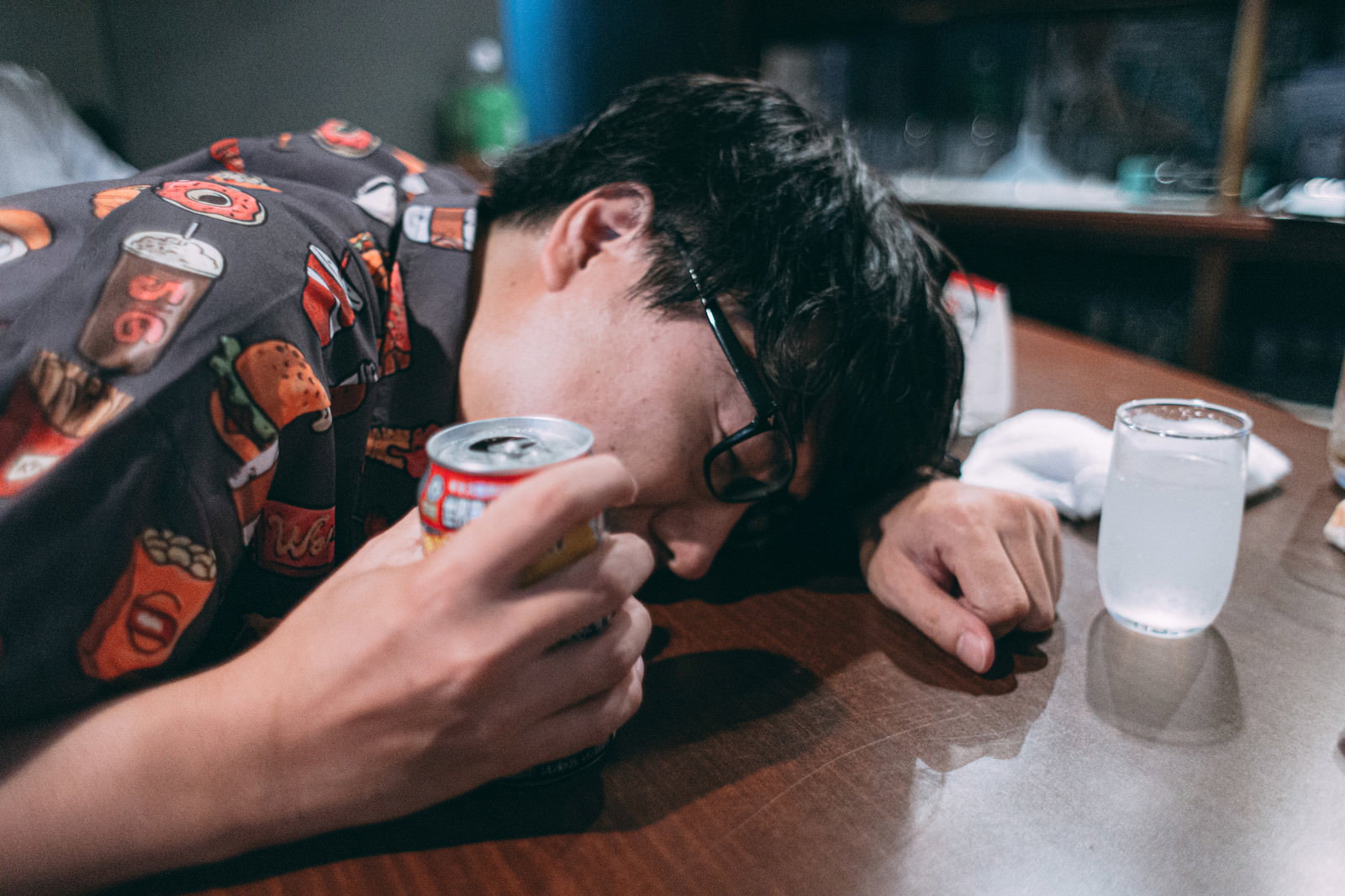 テーブルに突っ伏して酔い潰れている眼鏡をかけた男性［モデル：真崎真幸］