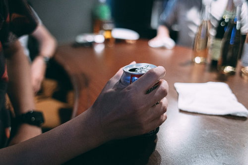 テーブルの上で缶を握りしめる手のクローズアップ