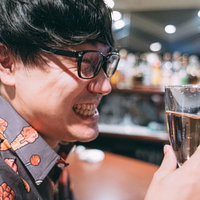 バーカウンターでシャンパンで乾杯する眼鏡の男性の写真