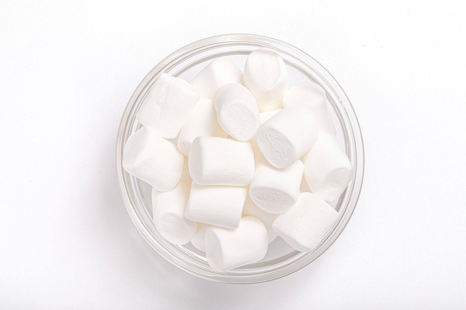 透明なガラス容器に入った白いマシュマロが白い背景で撮影された写真