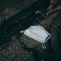 アスファルトに落ちているポイ捨てマスクの環境汚染の写真