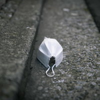 道端に捨てられた白いマスクの写真