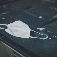 アスファルトの上に捨てられた白いマスクの写真