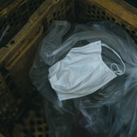 地面に散乱したゴミと一緒に投棄されたマスクの写真